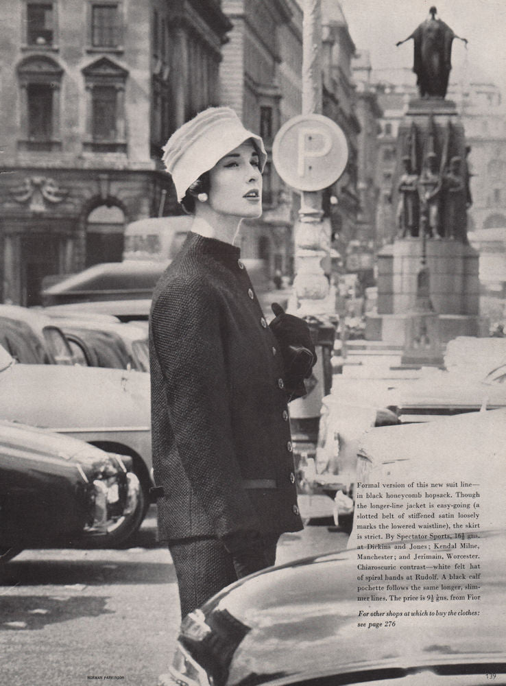 Black honeycomb hopsack suit. White felt Rudolf hat. Fashion. BRITISH VOGUE 1955